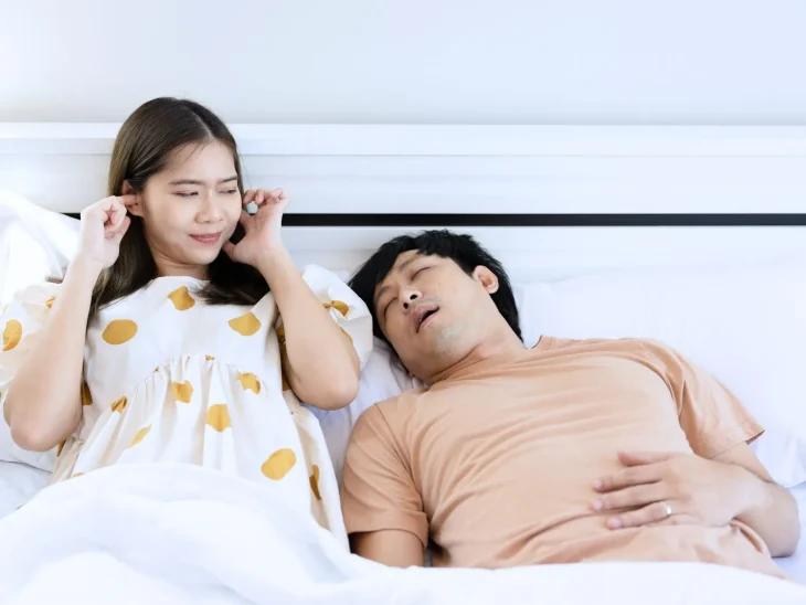 Woman annoyed by her partner snoring loudly in bed